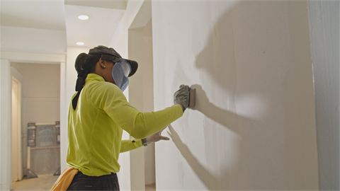A photo of Zjanice Carter sanding drywall.